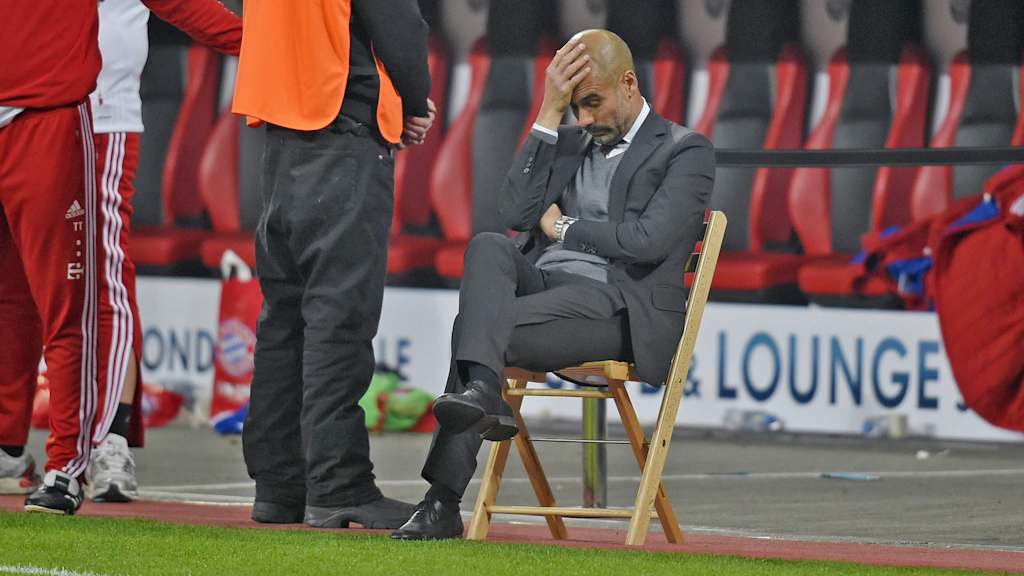 Pep Guardiola sitzt auf einem Klappstuhl im Leverkusener Stadion.