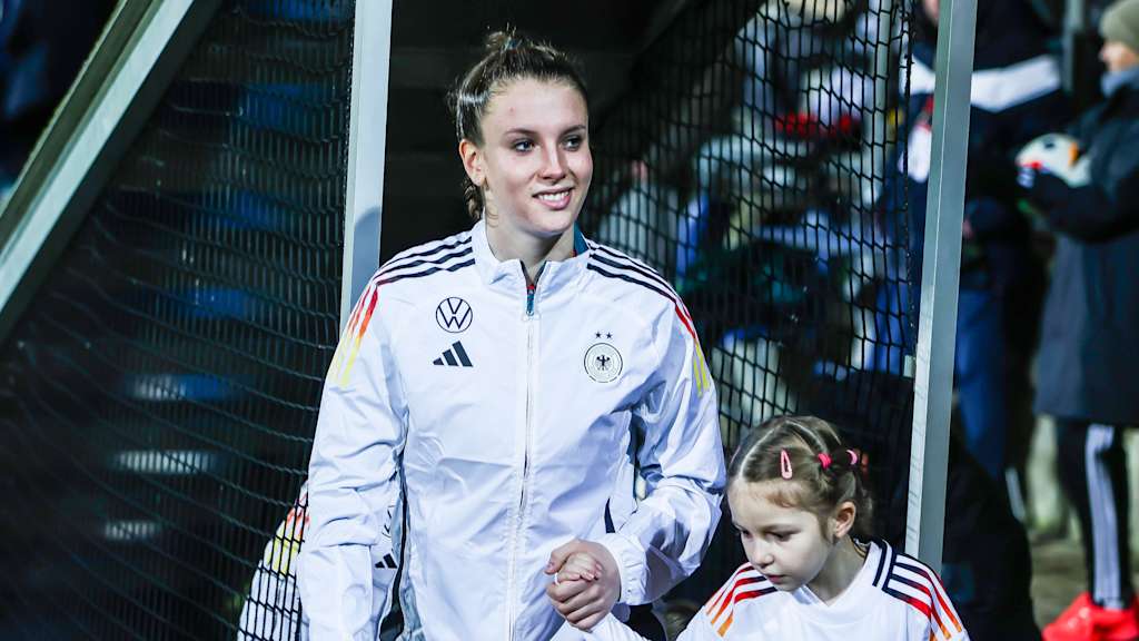 Ena Mahmutovic läuft mit einem Einlaufkind an der Hand aus den Katakomben und lächelt.