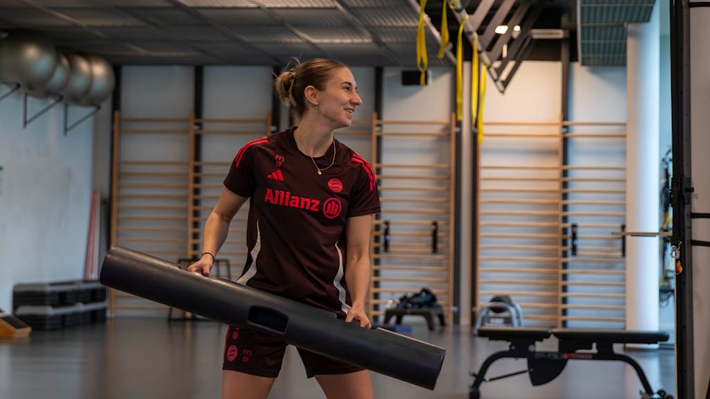 Katharina Naschenweng stemmt mit beiden Händen ein Gewicht im Reha-Bereich des FC Bayern Campus.