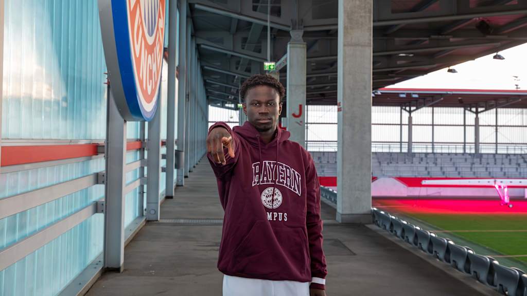 Bajung Darboe points to the camera at the FC Bayern Campus stadium.