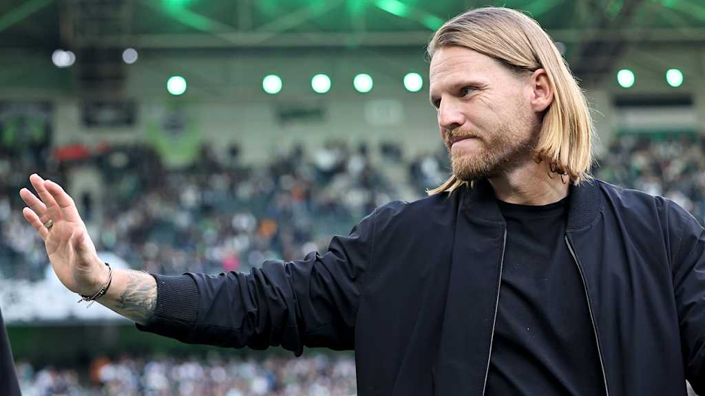 El entrenador del Gladbach, Eugen Polanski, saluda con la mano.