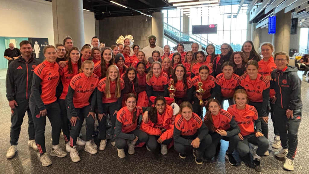 Die U17 und U15 der FC Bayern Frauen im Gruppenfoto mit zwei Pokalen und Vincent Kompany im Hintergrund