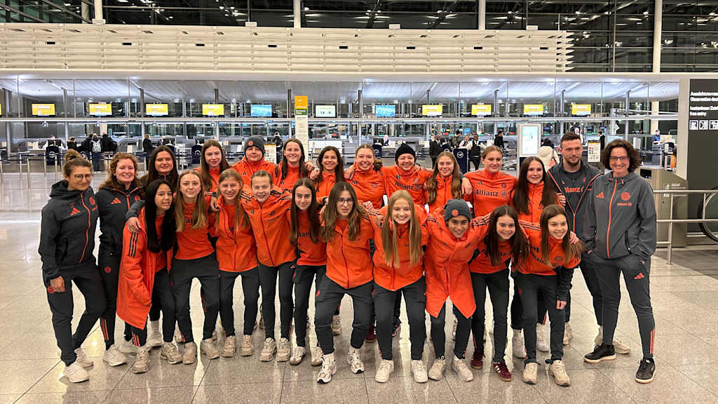 Die U15 der FC Bayern Frauen posiert auf einem Mannschaftsfoto am Flughafen