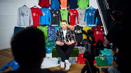 Manuel Neuer sitzt zwischen Trikots von sich und gibt ein Interview