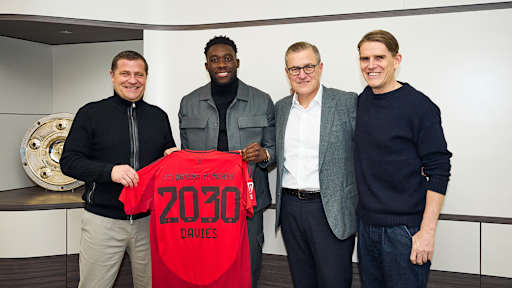 Max Eberl, Alphonso Davies, Jan-Christian Dreesen und Christoph Freund stehen nebeneinander und halten ein Trikot von Alphonso Davies hoch.