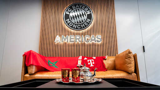 Auf einer Couch liegen ein FC Bayern Trikot von Saibari sowie eine marokkanische Flagge