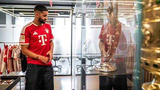 Ismael Saibari betrachtet in einem FC Bayern-Trikot Pokale in einer Vitrine