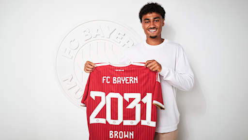 Nathaniel Brown hält ein FC Bayern-Trikot mit 2031 Brown