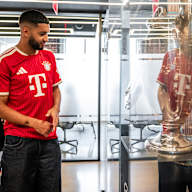 Ismael Saibari betrachtet in einem FC Bayern-Trikot Pokale in einer Vitrine