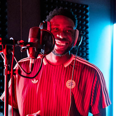 Alphonso Davies steht vor einem Mikro und lacht