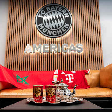 Auf einer Couch liegen ein FC Bayern Trikot von Saibari sowie eine marokkanische Flagge