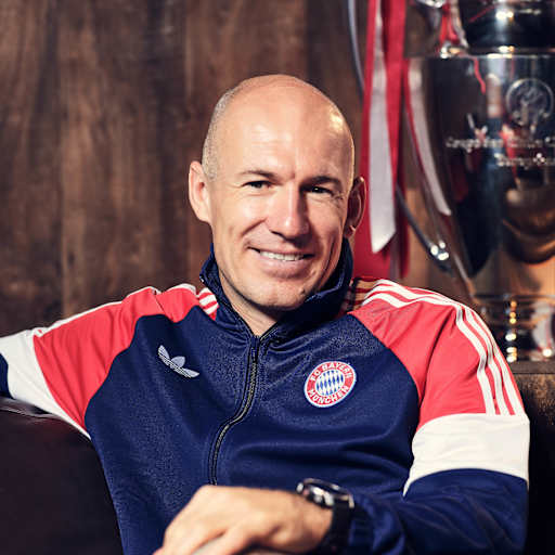 Arjen Robben sitzt auf einem Sofa vor dem Henkelpott und grinst