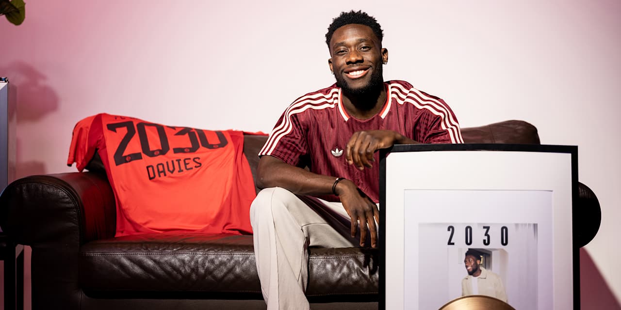 Alphonso Davies sitzt auf einer Couch und hält ein Albumcover mit 2030 im Arm
