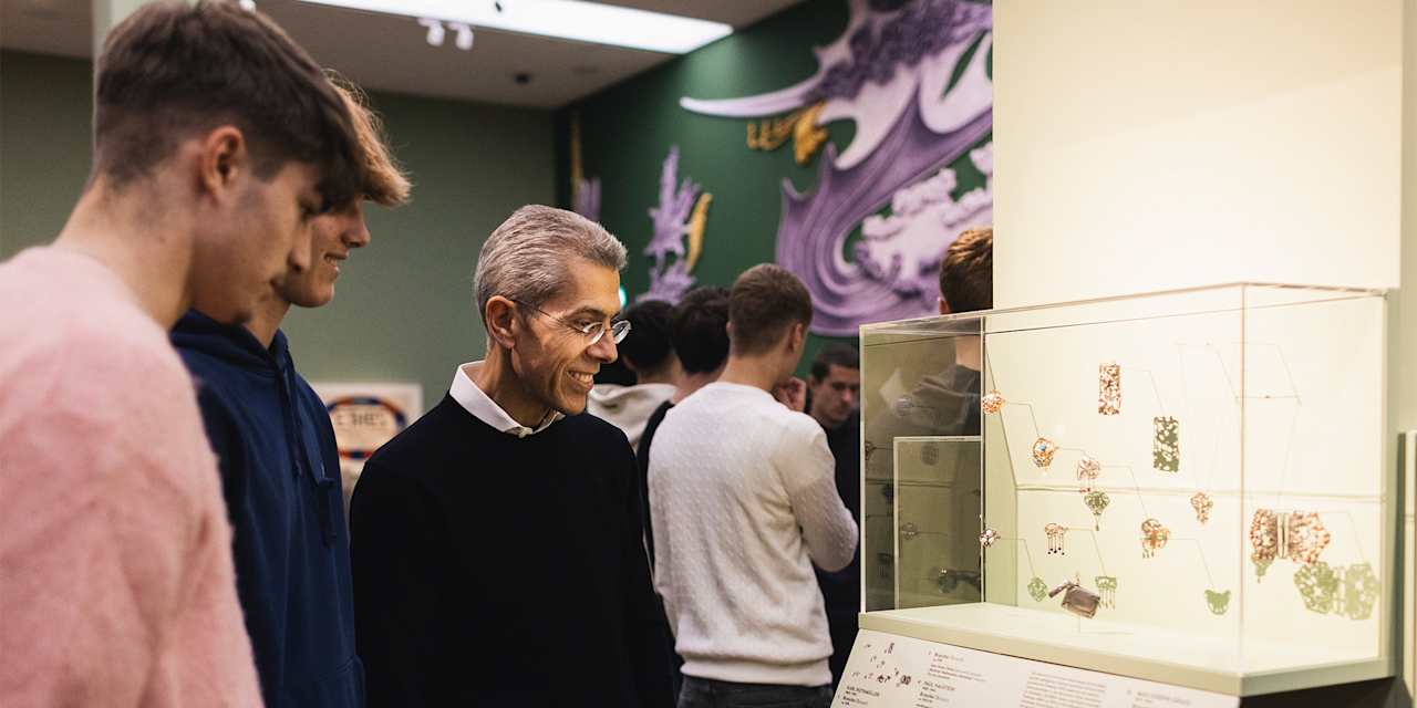 Michael Diederich betrachtet mit FC Bayern Campus-Talenten eine Vitrine in der Münchner Kunsthalle