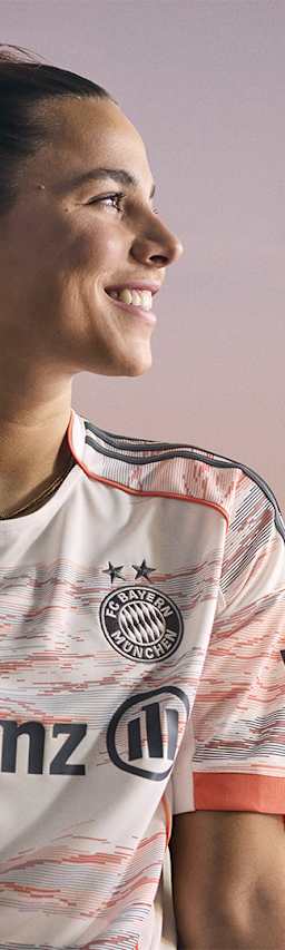 Lena Oberdorf im neuen Auswärtstrikot des FC Bayern für die Saison 2025/26 in Weiß, Grau und leuchtendem Coral.