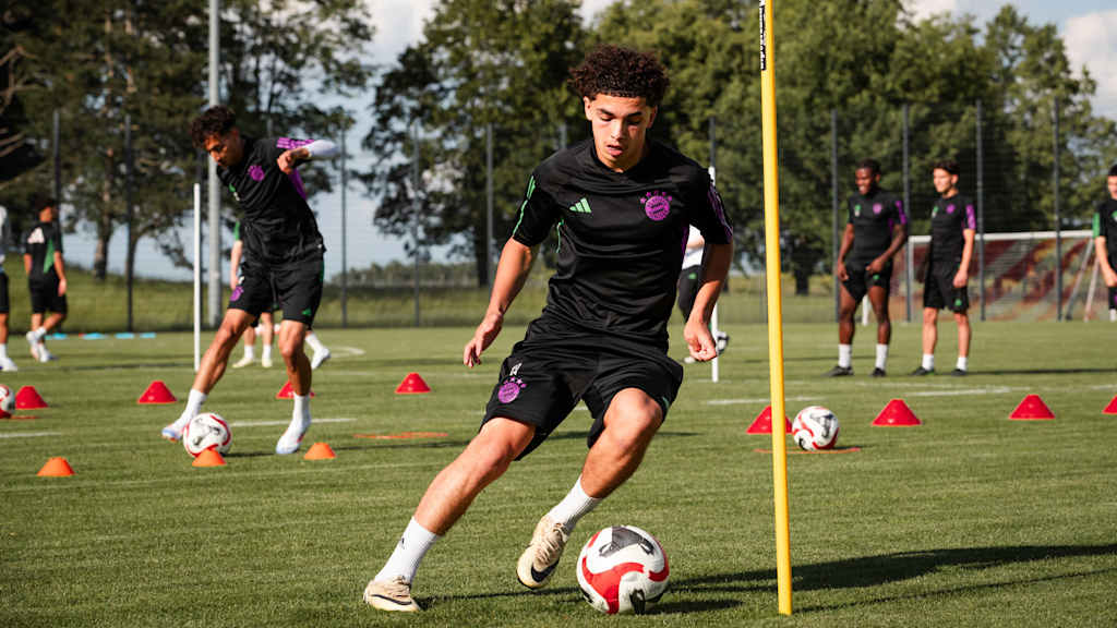 Ein Spieler der FC Bayern-Jugend umdribbelt eine Stange im Training mit dem Ball