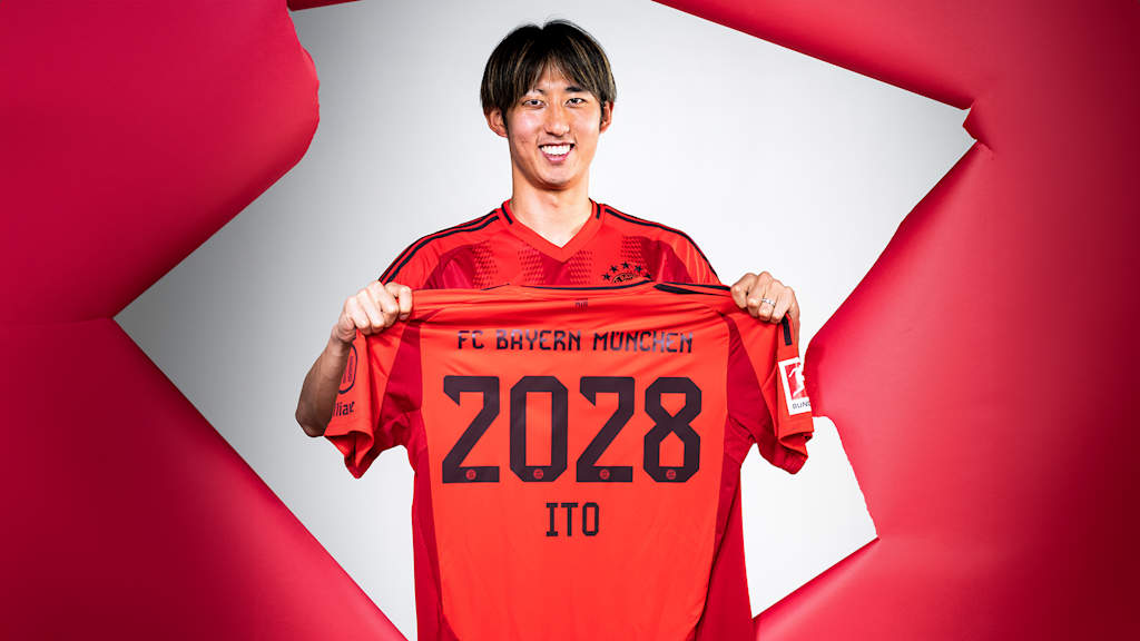 Hiroki Ito hält ein FC Bayern-Trikot mit der Zahl 2028 hoch.