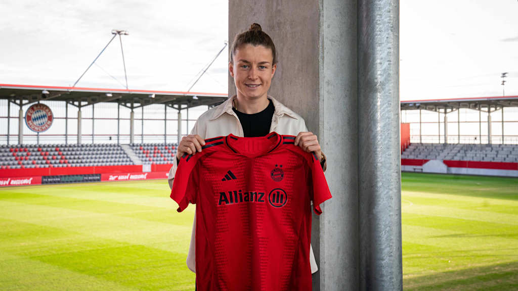 Michelle Ulbrich in the stands holding up an FC Bayern shirt for the camera