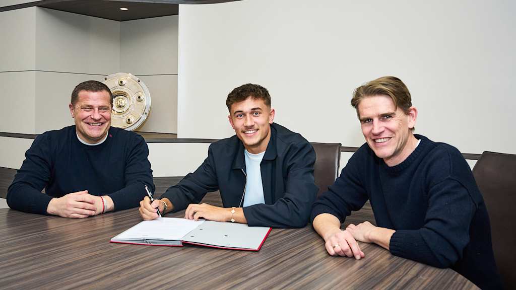 Tom Bischof unterschreibt seinen Vertrag beim FC Bayern. Neben ihm sitzen Max Eberl und Christoph Freund