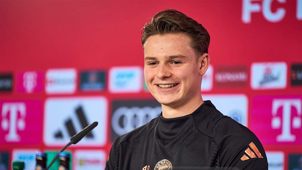Jonas Urbig lächelnd auf seiner Vorstellungs-Pressekonferenz beim FC Bayern