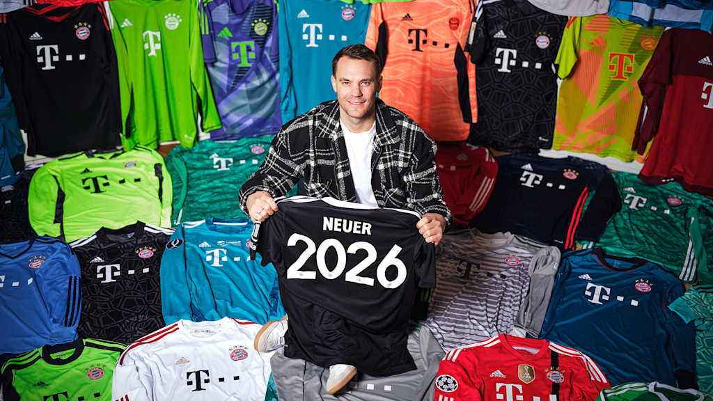 Manuel Neuer sitzt zwischen seinen Trikots des FC Bayern und hält ein Trikot mit der Neuer 2026 in der Hand