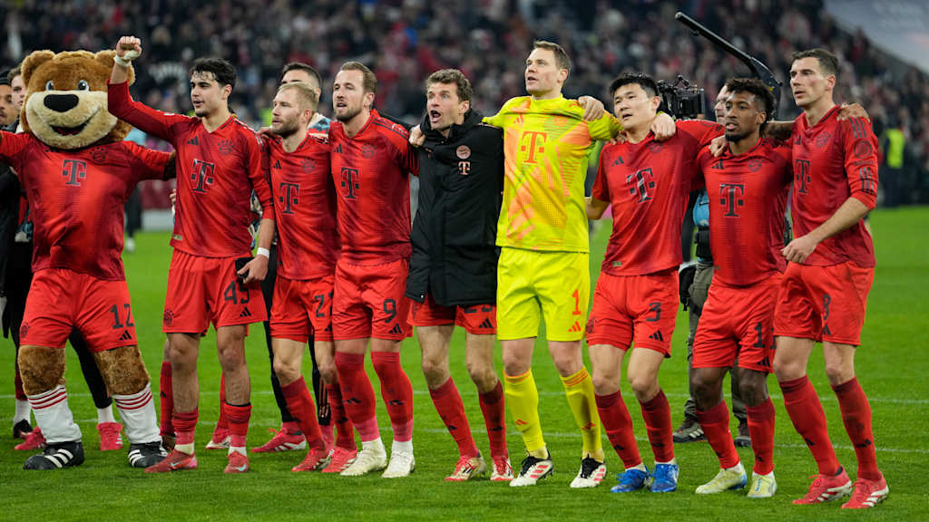 FC Bayern players celebrate arm in arm in front of the Südkurve.