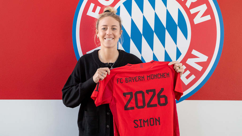 Carolin Simon posiert vor dem FC Bayern Logo mit einem Trikot mit der Rückennummer 2026.