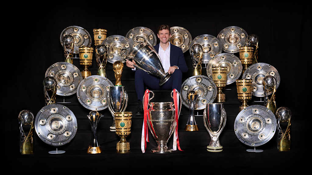 Thomas Müller inmitten der Pokale und Trophäen, die er in seiner Zeit beim FC Bayern gewonnen hat.