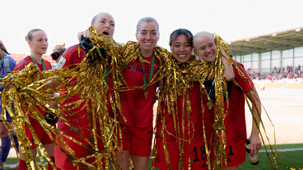 Magdalena Eriksson, Linda Sembrant, Momoko Tanikawa und Pernille Harder von den FC Bayern Frauen stehen Arm in Arm mit Lametta um den Hals auf dem Platz und lächeln in die Kamera.