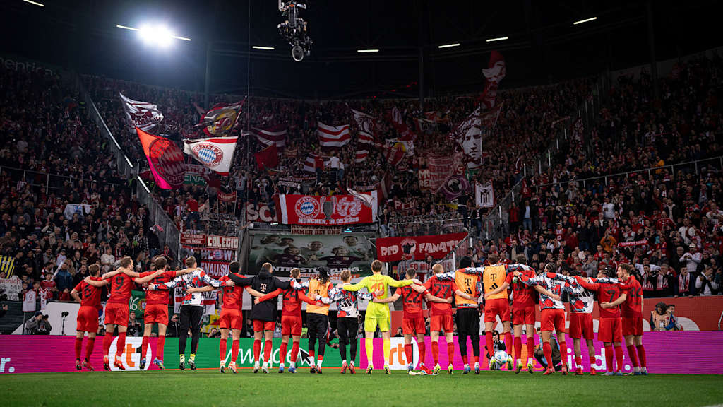 Die Spieler des FC Bayern hüpfen vor der Auswärts-Fankurve in Augsburg