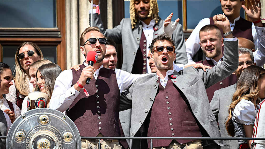 Harry Kane und Thomas Müller singen auf dem Rathausbalkon des Münchner Marienplatz