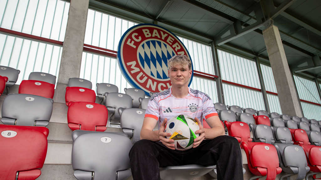 Richard Meier sitzt im Stadion am FC Bayern Campus und trägt dabei das Auswärtstrikot des FC Bayern.