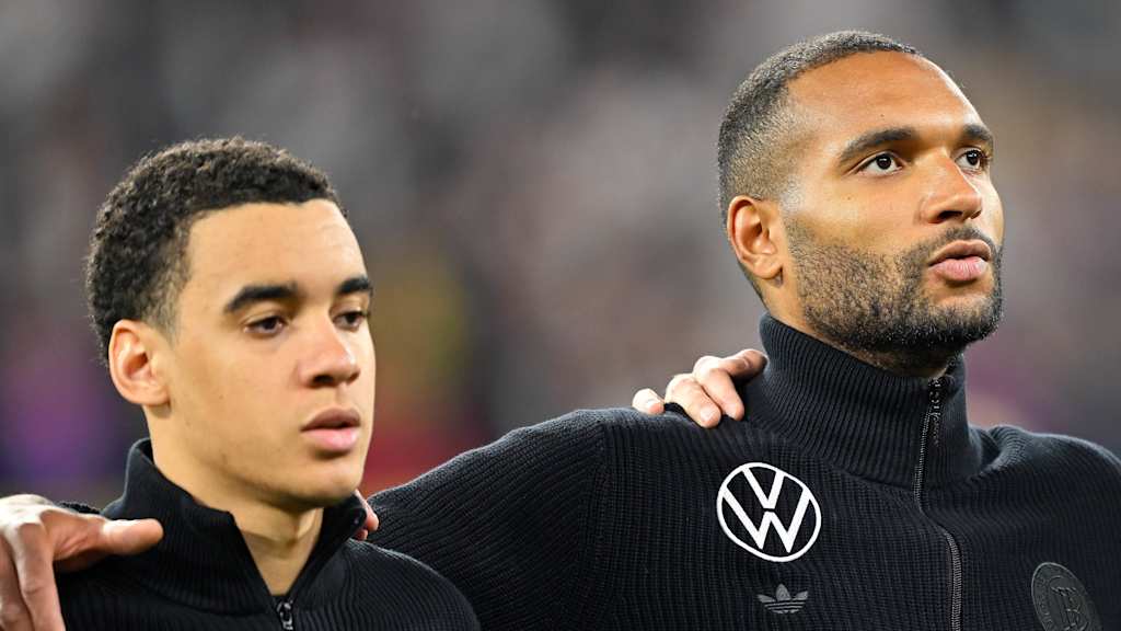Jonathan Tah arm in arm with Jamal Musiala.