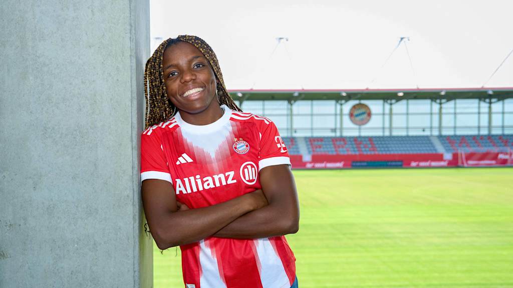 Edna Imade mit verschränkten Armen und einem Lächeln in der Spielstätte am FC Bayern Campus.