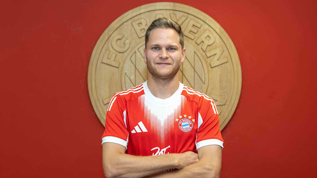 Beno Schmitz posiert vor einem FC Bayern Wappen.