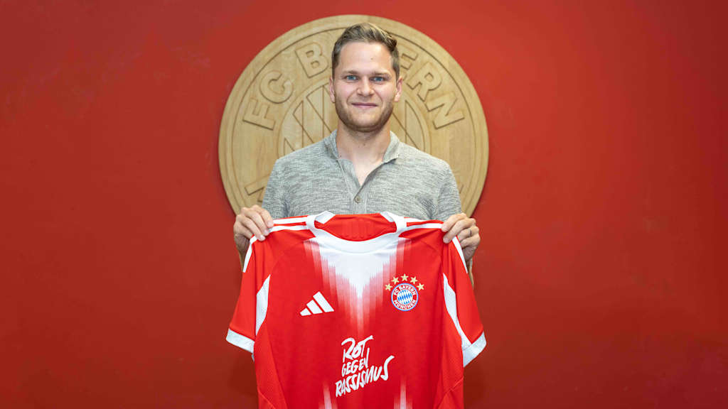 Benno Schmitz hält das Trikot des FC Bayern in die Luft.