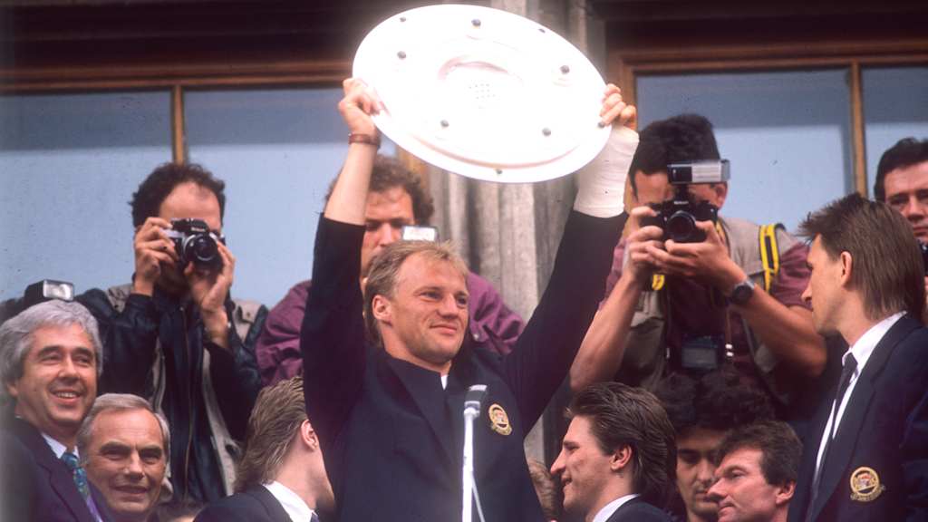 Meisterfeier auf dem Marienplatz 12.05.1990. Hansi Pflügler präsentiert die Meisterschale. Im Hintergrund rechts: Thomas Kastenmaier, Co-Trainer Egon Coordes und Klaus Augenthaler. Links: Präsident Dr. Fritz Scherer und Oberbürgermeister Georg Kronawitter.