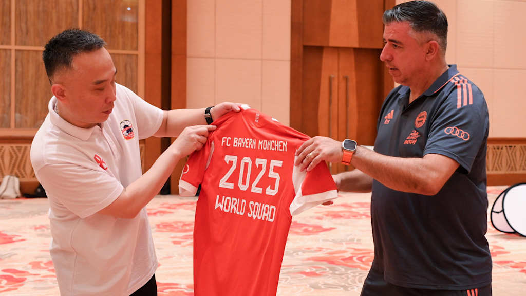 FC Bayern World Squad coach Roy Makaay hands over a jersey to the coach of the Shanghai Blind Football Team