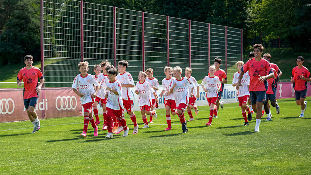 The FC Bayern World Squad 2025 players warming up with the kids
