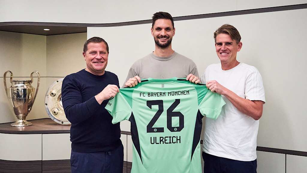 Max Eberl, Sven Ulreich y Christoph Freund sostienen una camiseta de portero con el número 26 y Ulreich