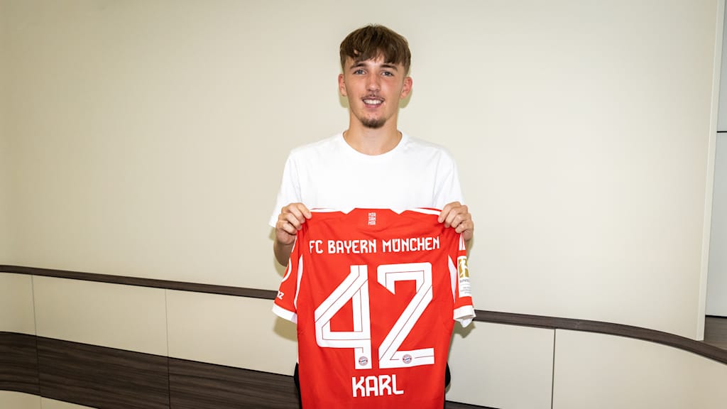 Lennart Karl holding his FC Bayern jersey in front of a red background.