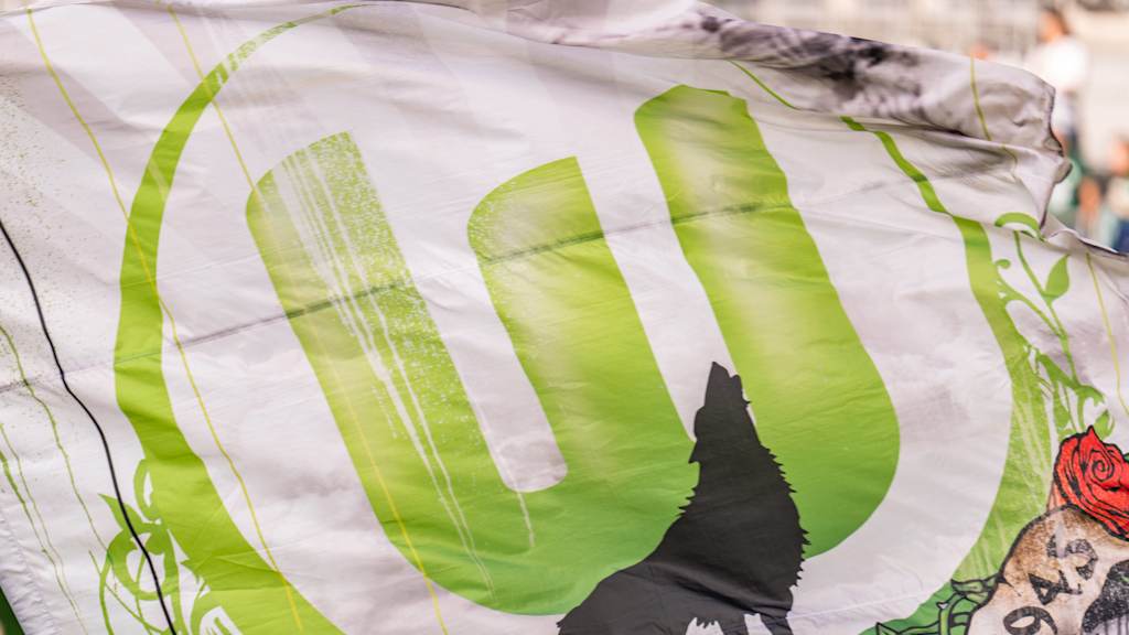 Eine Flagge mit dem Logo des VfL Wolfsburg. Im Vordergrund steht die Silhouette eines heulender Wolfs.