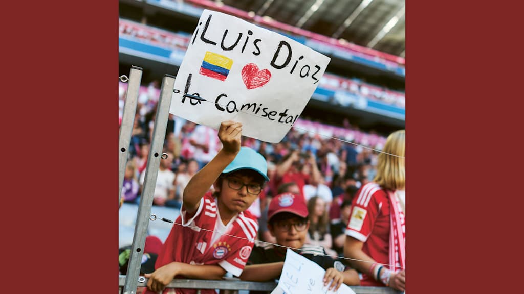 Ein junger kolumbianische Fan hält ein Schild für Luis Diaz in der Allianz Arena hoch.