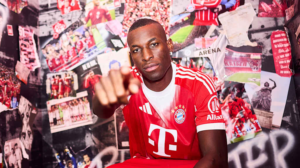 Nicolas Jackson trägt ein FC Bayern Trikot und zeigt mit dem Finger in die Kamera
