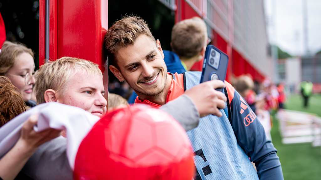 Josip Stanisic macht ein Selfie mit einem Fan beim Training des FC Bayern