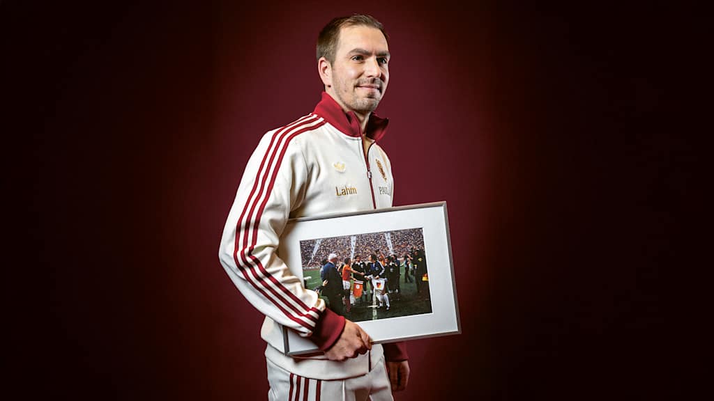Philipp Lahm holds a framed picture of Franz Beckenbauer in his hand.