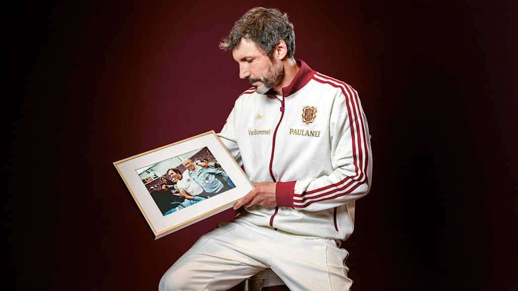 Mark van Bommel holds a framed picture of Franz Beckenbauer in his hand.