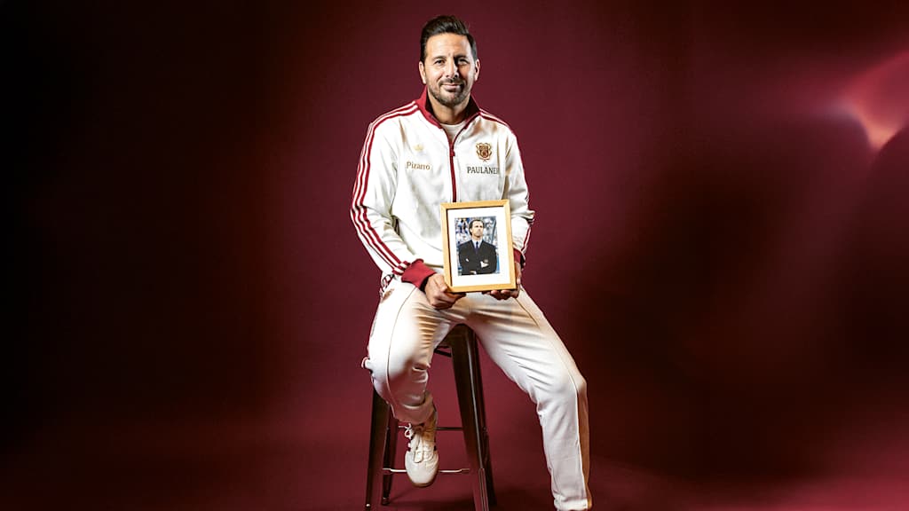 Claudio Pizarro holds a framed picture of Franz Beckenbauer in his hand.