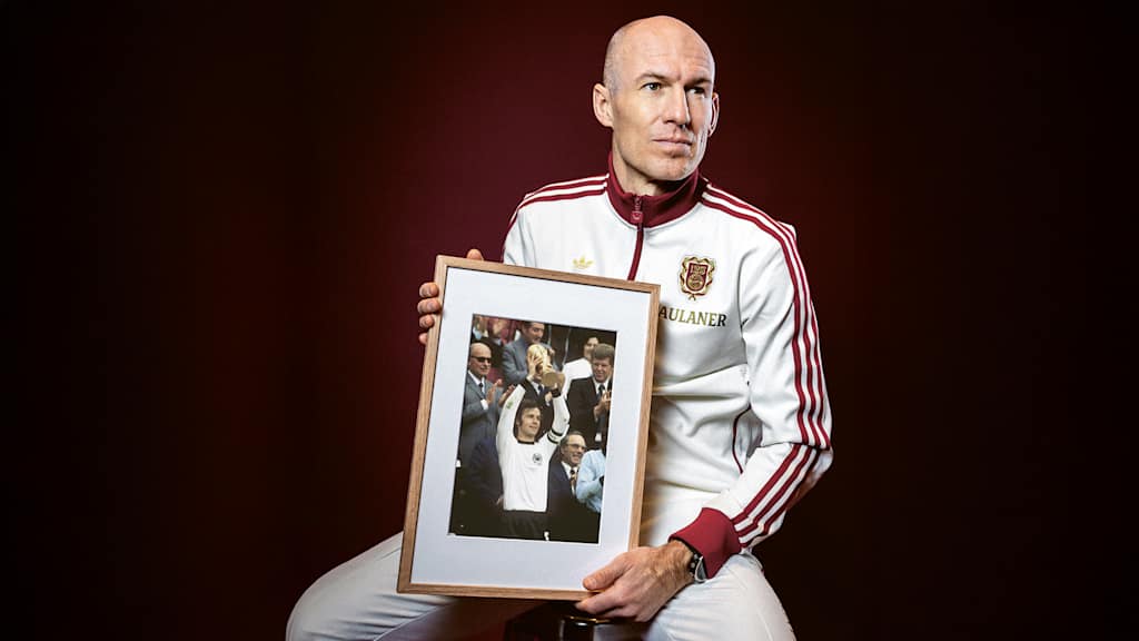 Arjen Robben holds a framed picture of Franz Beckenbauer in his hand.