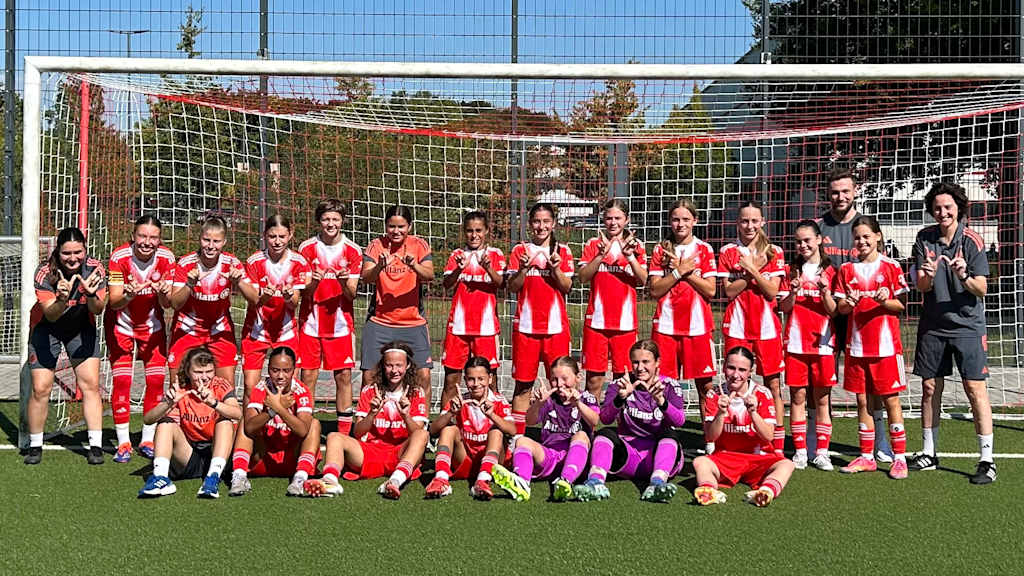 Die Spielerinnen der U15 zeigen auf einem Gruppenbild vor dem Tor ein 'W' mit ihren Fingern.